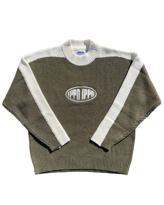 Folded green sweater with white trim on a gray surface